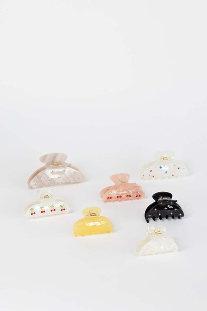 Summer Bliss HAIR CLIP shown among a wide flat-lay assortment of seven differently shaped and colored hair clips, studio shot.
