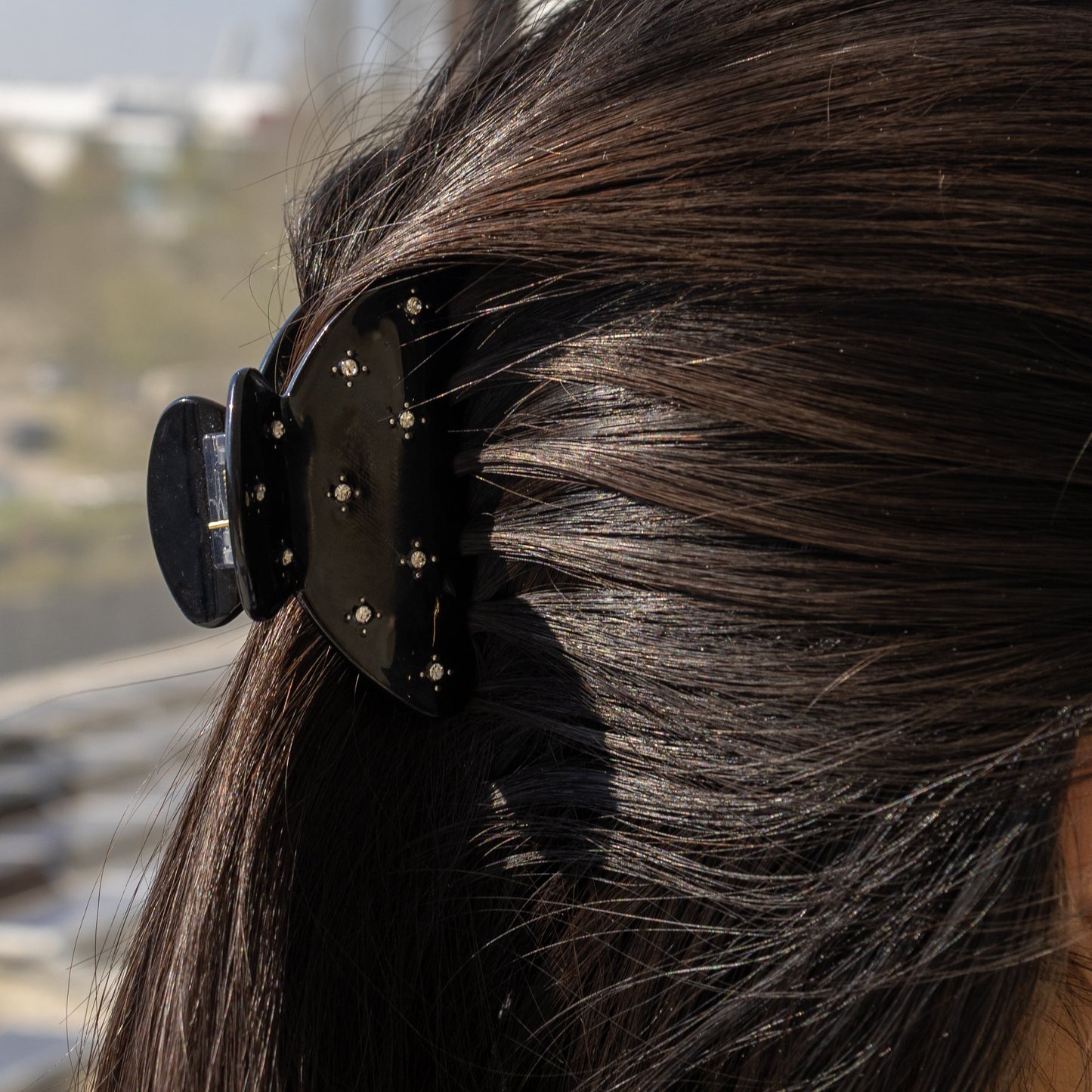 Summer Bliss HAIR CLIP in solid black, worn holding a low ponytail on dark hair, close-up side view.