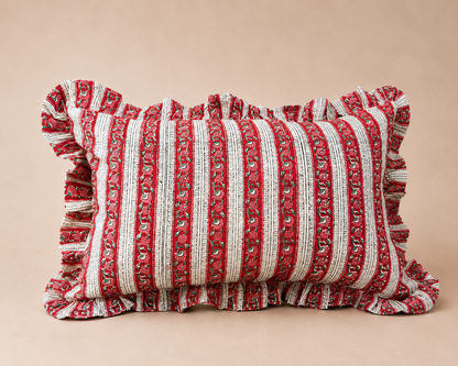 Red and cream striped lumbar cushion with a floral border pattern and ruffled edge, the Suni Red Rectangle Cushion on a neutral background.