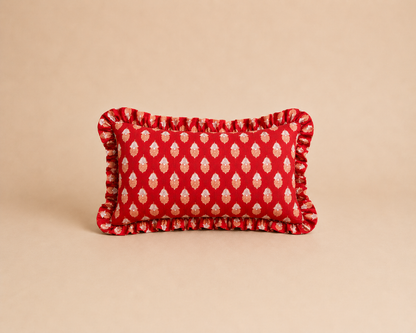 Sunset Motif Rectangle cushion in red with a repeating cream and orange paisley leaf print and a ruffled border on a warm backdrop.