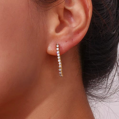 Close-up of a Sweet Thing Earring worn on the ear in gold, the crystal-lined oblong hoop hanging down.