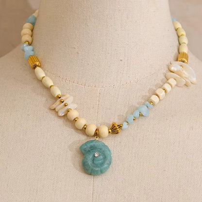 The Tahiti NECKLACE displayed on a mannequin bust, its cream beads and carved shell pendant shown in close, detailed focus.