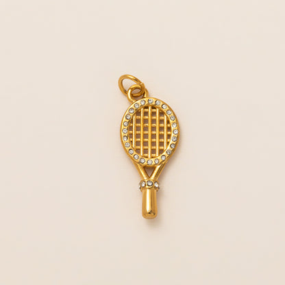 The Tennis Racket CHARM in gold, a racket-shaped pendant with a pave-set frame and grip, shown in close-up studio photography.