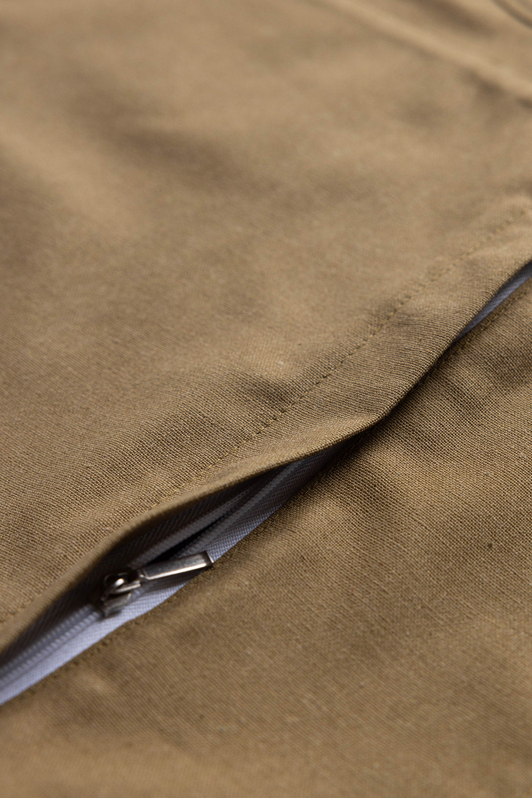 Close-up of the Terry Rectangle Linen cushion's khaki fabric weave and hidden zipper closure along its edge.