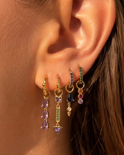Close-up of the Tessa Set worn as an ear stack, four huggie hoops each with a colorful gemstone drop charm.