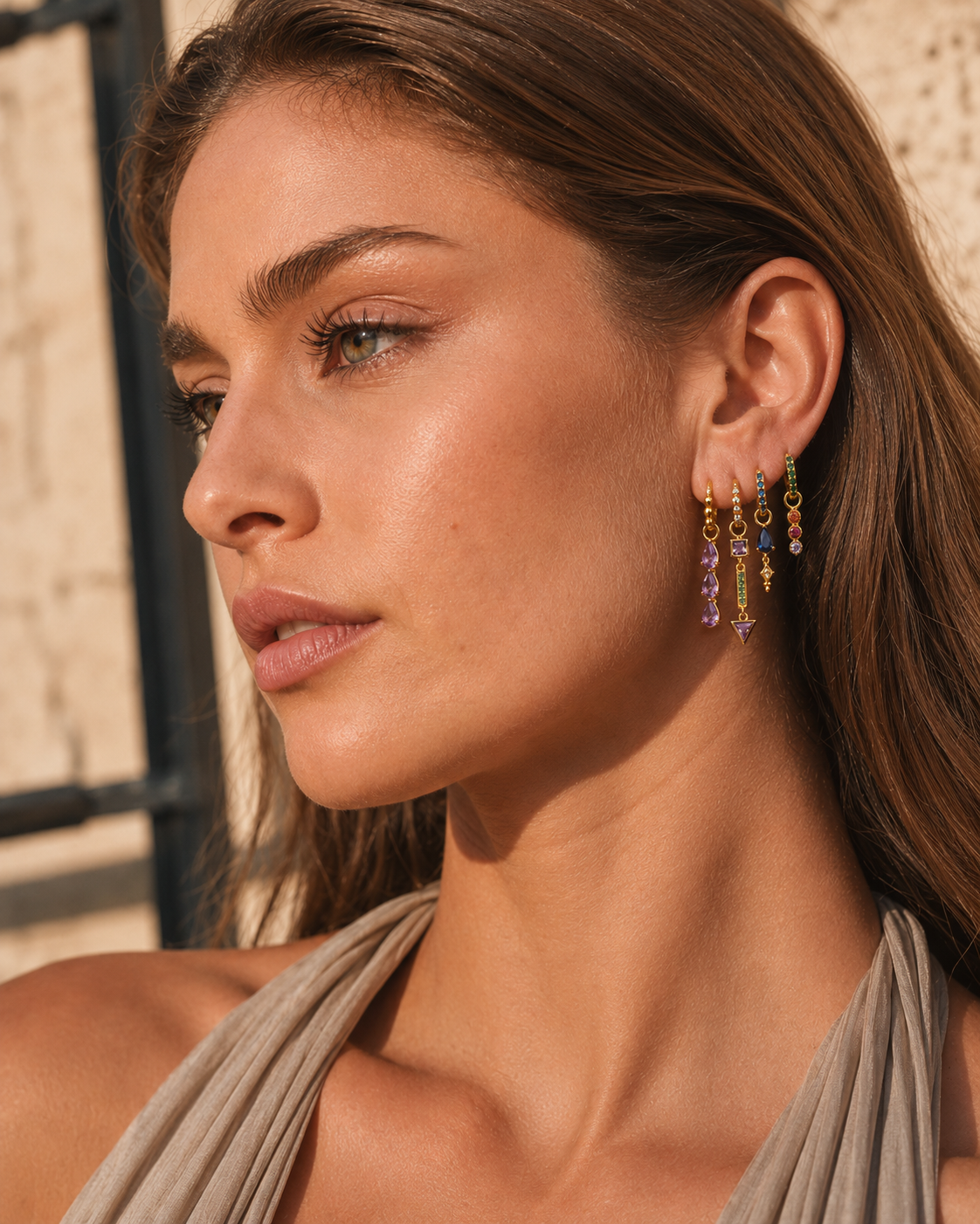 Tessa Set worn outdoors in profile, showing the stacked huggie hoops with amethyst, sapphire, and emerald drops.
