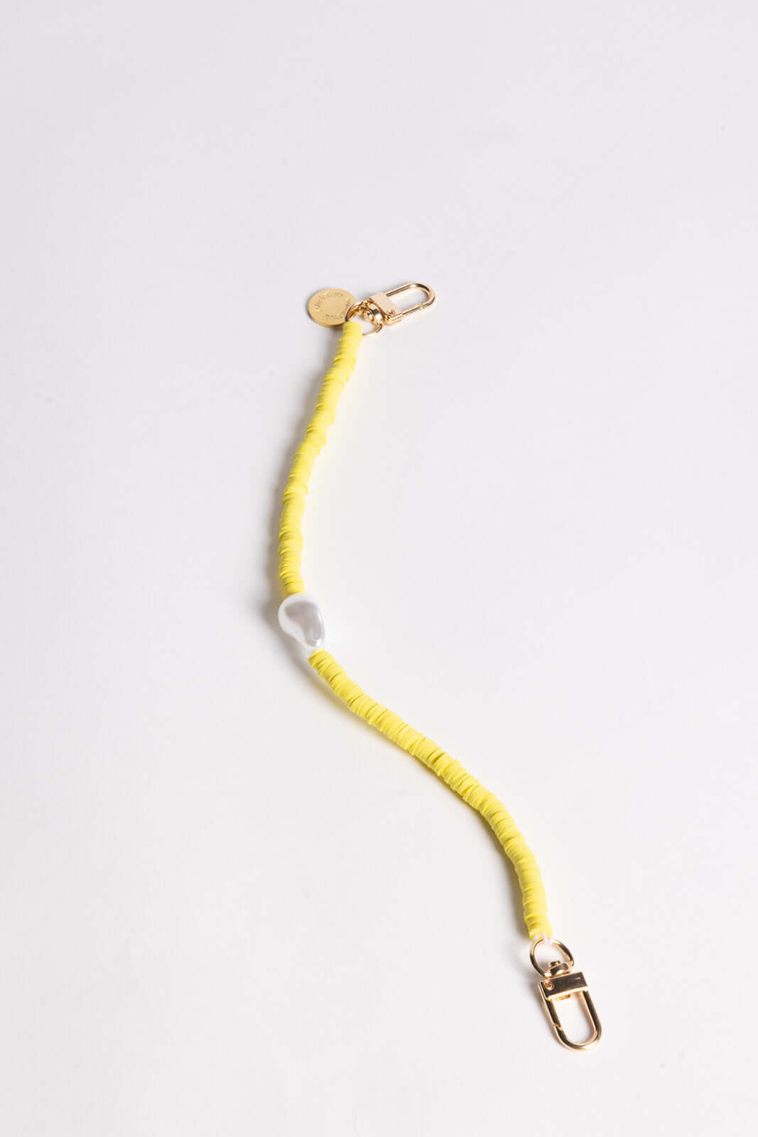 A yellow heishi bead phone cord with a white bead and gold clasps, shown on a white background.