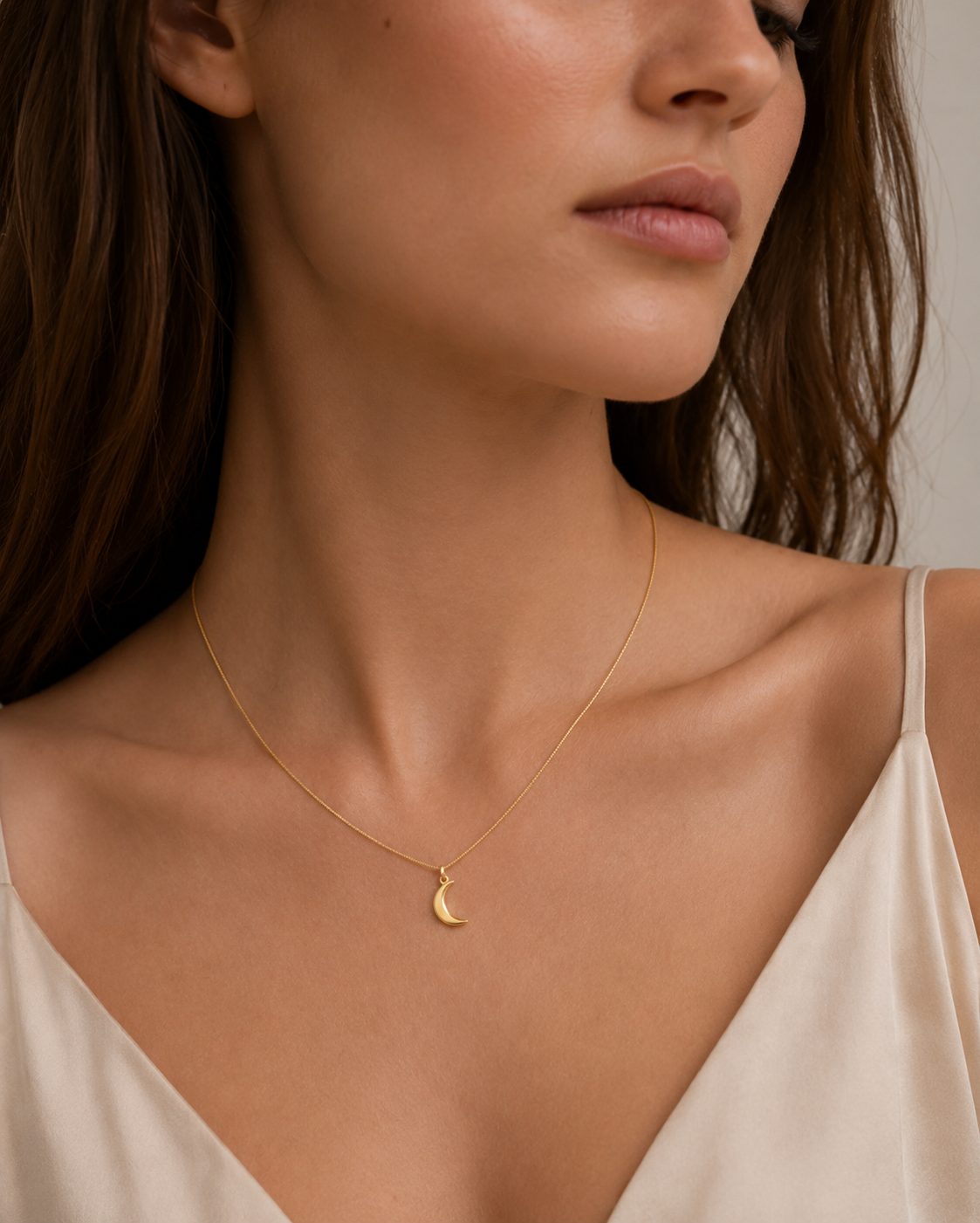 Gold crescent moon charm from the Signature Charms BUNDLE, worn on a delicate gold chain close to the neckline.