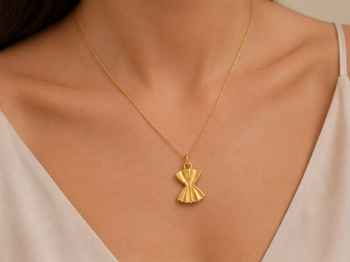 Gold farfalle pasta charm from the Signature Charms BUNDLE worn on a fine gold chain necklace at the neckline.