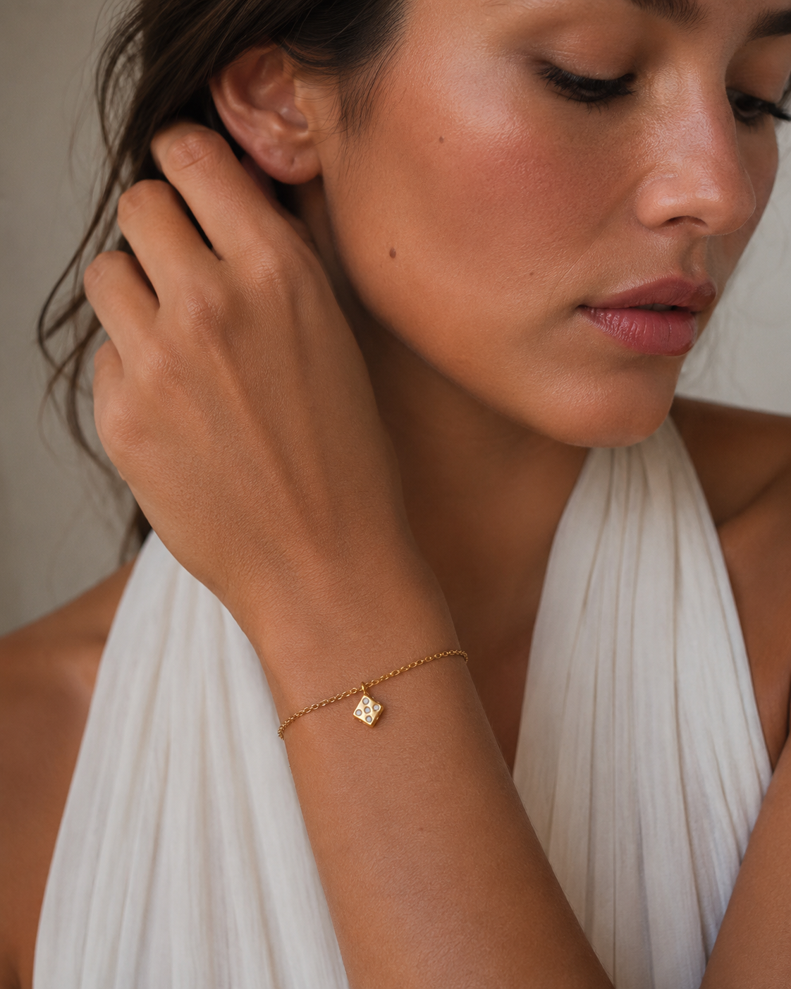Gold dice charm set with tiny stones from the Signature Charms BUNDLE, worn on a chain bracelet close-up on the wrist.