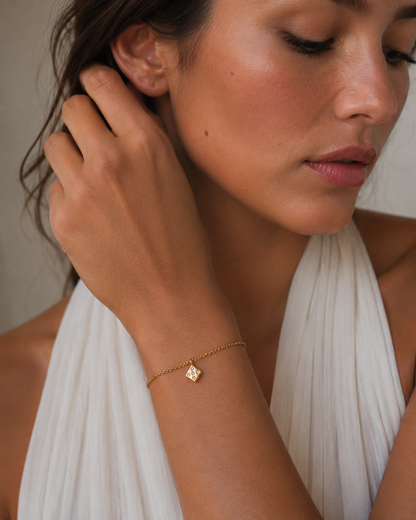 Gold dice charm set with tiny stones from the Signature Charms BUNDLE, worn on a chain bracelet close-up on the wrist.