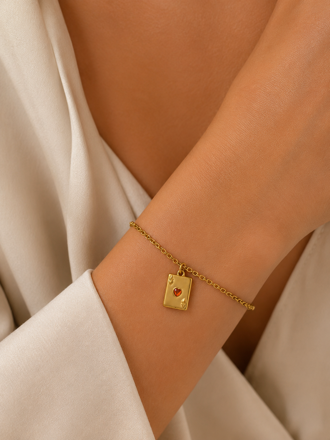 Gold ace of hearts card charm from the Signature Charms BUNDLE, worn on a chain bracelet close-up on the wrist.
