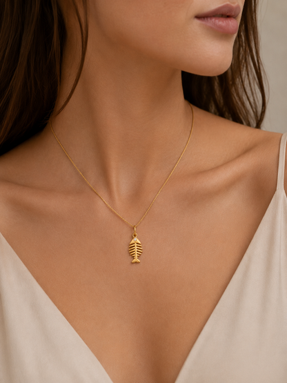 Gold fishbone charm from the Signature Charms BUNDLE, worn on a fine gold chain necklace close to the neckline.