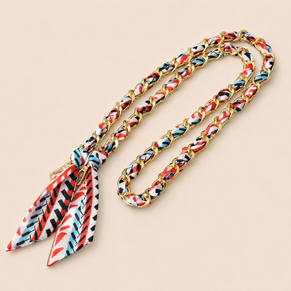 Red, black, and blue geometric-print silk scarf woven through a gold chain-link Tossa phone chain.