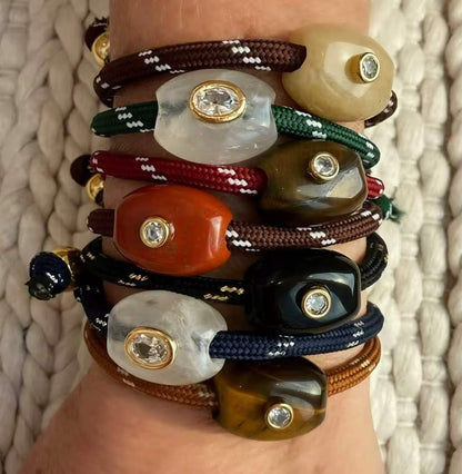 Wrist stacked with Truffle BRACELET rope cords in seven colours, each with a polished stone and gold-set crystal, wholesale jewelry