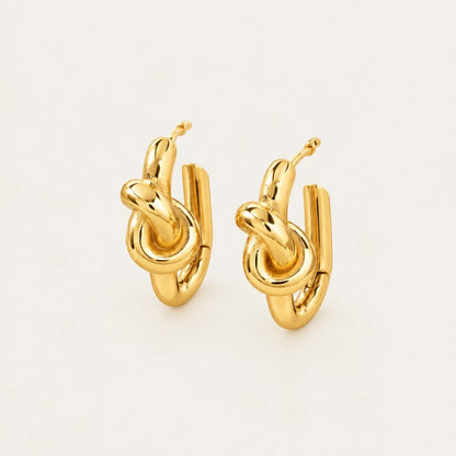 Front view of gold Twine EARRINGS with a polished knotted design on a cream background — Folie à Trois wholesale jewelry