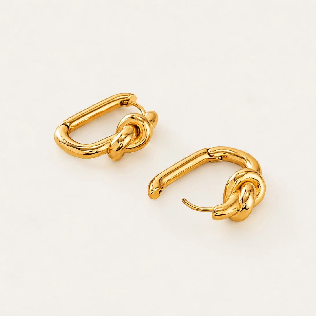 Gold Twine EARRINGS lying flat with the click hinge open, showing the oval hoop and knot detail — Folie à Trois