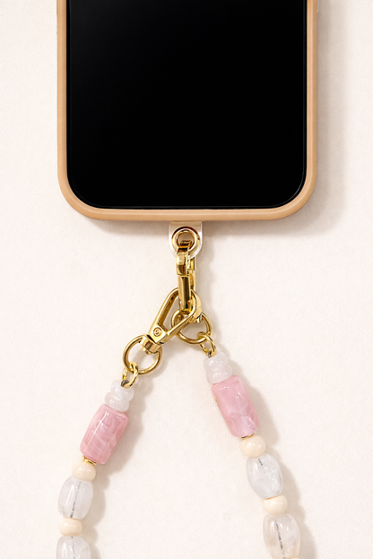 Close-up of the Universal Phone Adapter gold clasp attaching a white, pink, and coral beaded strap to a cream phone case.