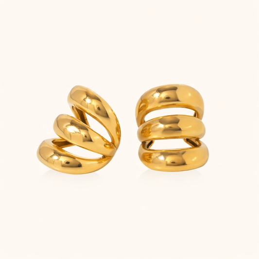 Unruly ear cuffs in gold, a triple-band spiral design wrapping around the ear in a bold sculptural shape.
