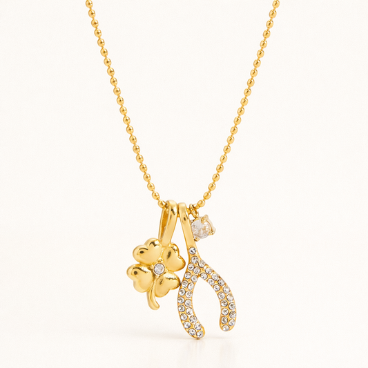 The Untamed NECKLACE in gold, its pave four-leaf clover and wishbone charms with a crystal drop shown on a ball chain.