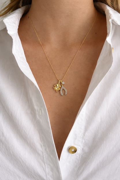 The Untamed NECKLACE worn at the neckline over a white shirt, its clover and pave wishbone charms resting together.