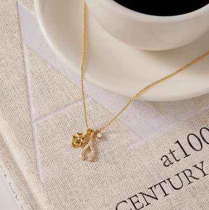The Untamed NECKLACE styled beside a coffee cup on a linen-covered book, its clover and pave wishbone charms in close focus.