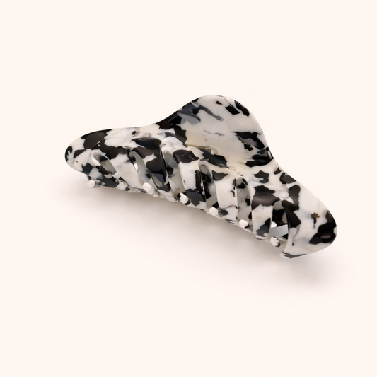 Black and white cow-print acetate claw clip from the Utopia HAIR CLIP collection, on a cream studio background.