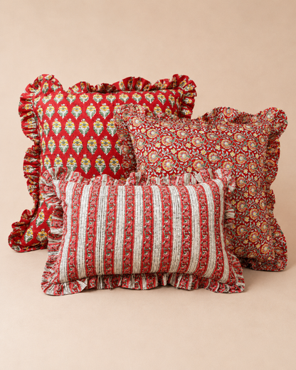 Three ruffled red cushions in leaf, floral medallion and striped patterns styled together, representing the Varsha, Suni and Sonal cushions.