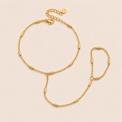 Venus Hand Chain BRACELET in gold with a bar-station chain linking wrist and ring, shown flat on a beige background.