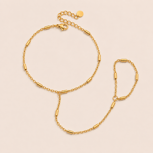 Venus Hand Chain BRACELET in gold with a bar-station chain linking wrist and ring, shown flat on a beige background.