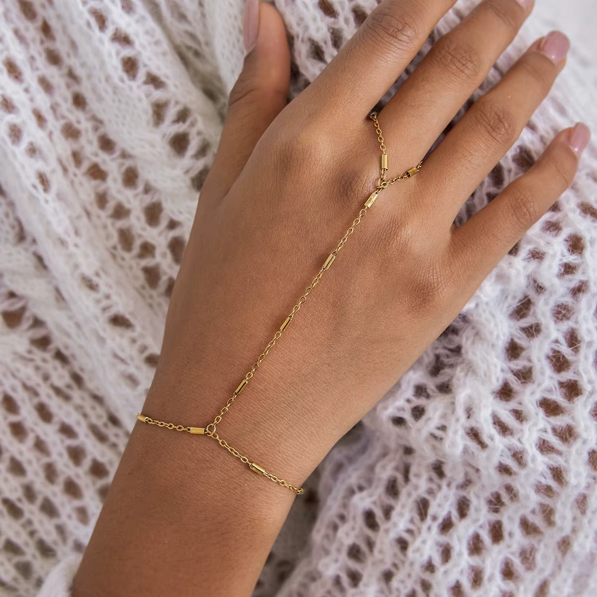 Venus Hand Chain BRACELET worn on the hand with a knit sweater in the background, delicate gold bar-station chain.