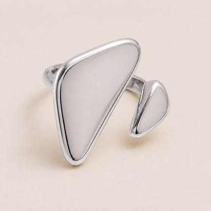 Silver asymmetric ring with a large flat triangular face and a smaller teardrop accent, on a cream backdrop — Folie à Trois Vénus RING.