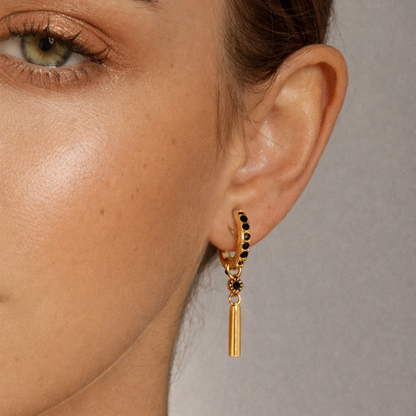 Worn close up, Vibrant Hues Earrings show their pave hoop and slim bar charm dangling in a striking black colorway.
