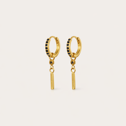 Vibrant Hues Earrings appear here in gold with black pave stones lining the hoop above a slim dangling bar charm.