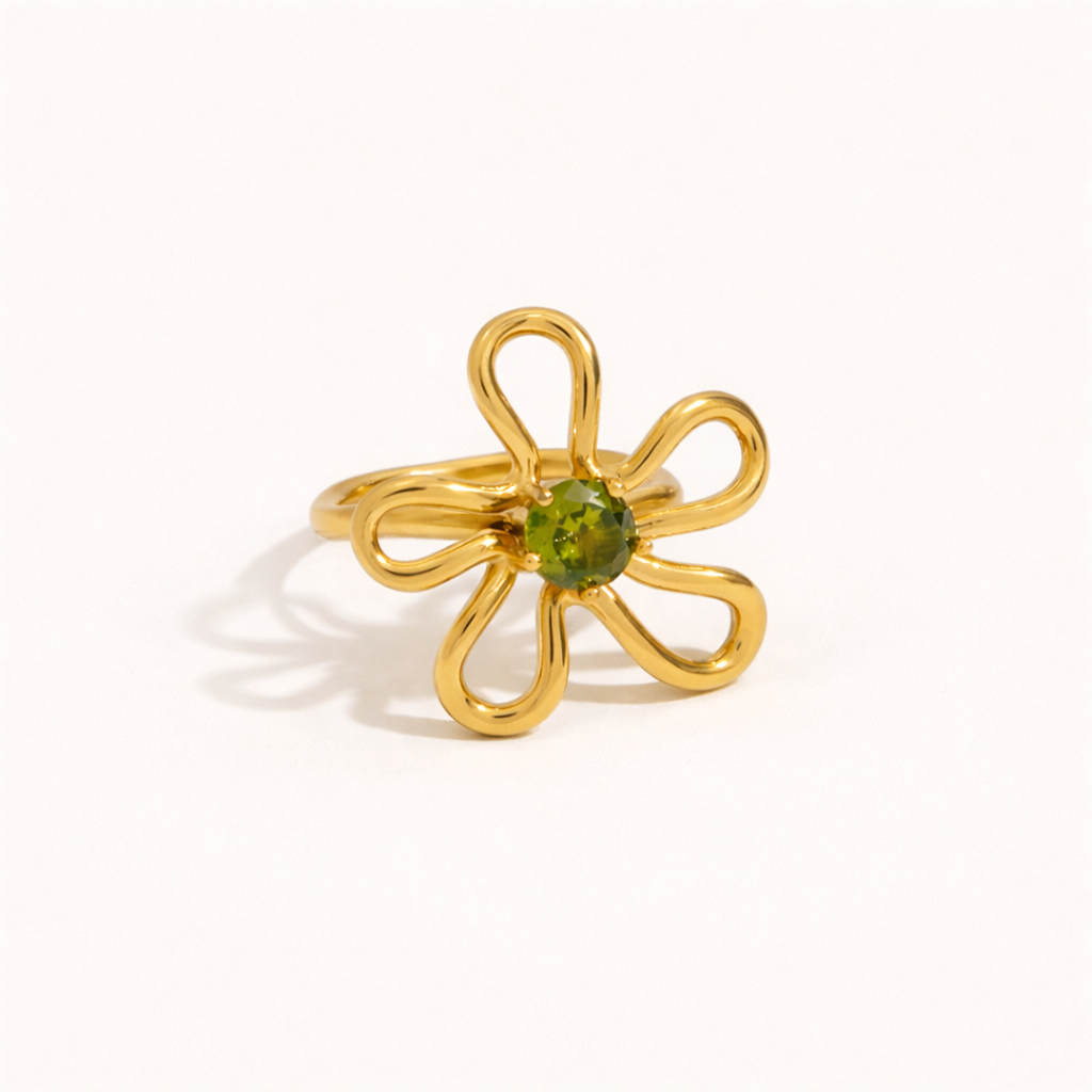 Gold wire-flower Vida RING set with a green stone center, shown at an angle on a cream backdrop.