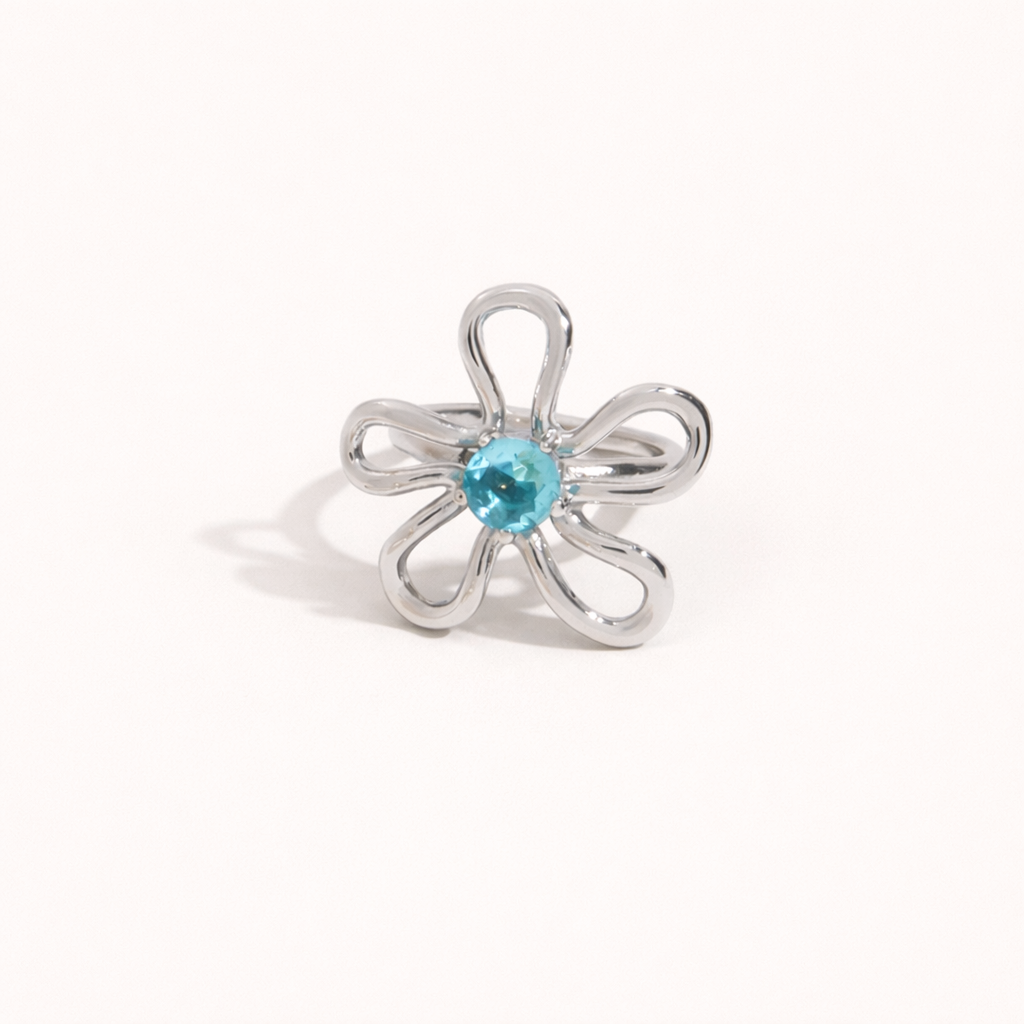 Silver wire-flower Vida RING set with a blue stone center, shown at an angle on a cream backdrop.