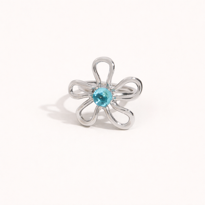 Silver wire-flower Vida RING set with a blue stone center, shown at an angle on a cream backdrop.