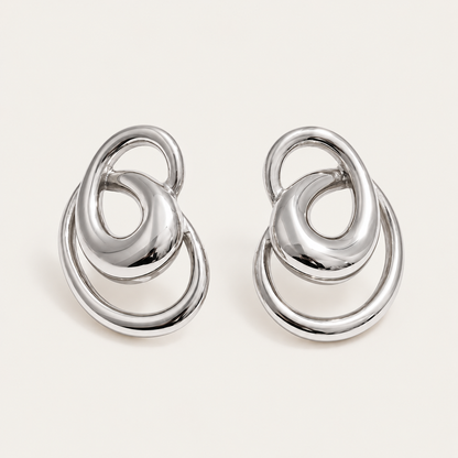 Pair of silver interlocking-ring stud earrings in a sculptural knot shape, product shot for the Folie à Trois Vortex EARRINGS.