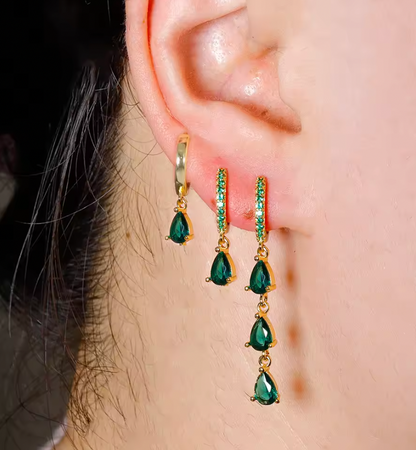 Waterfall Earrings worn close on the ear with green crystal drops cascading down beside a plain gold huggie hoop.