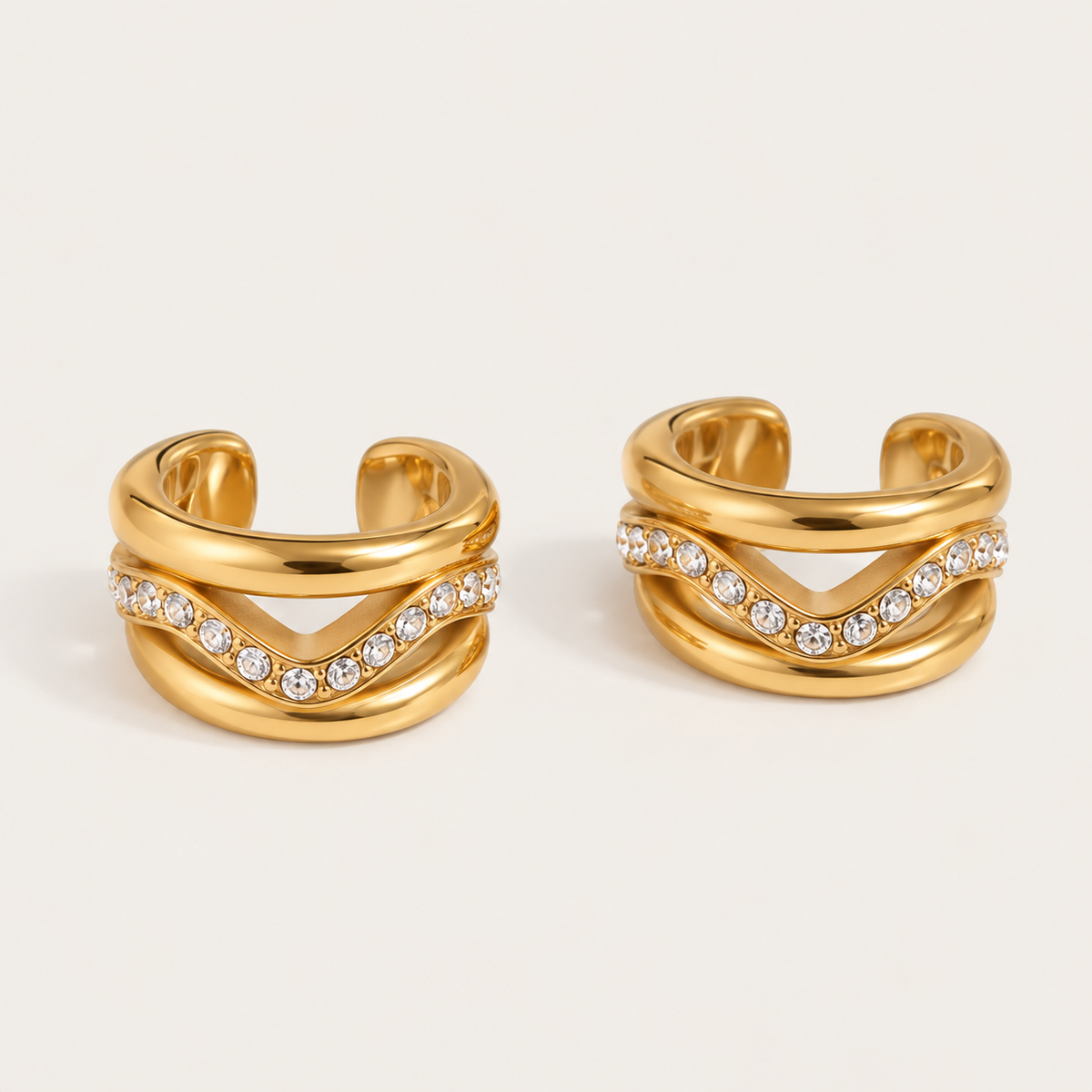 Pair of gold ear cuffs with an open wave band and a single row of pavé crystals, product shot for the Folie à Trois Wavelet EAR CUFF.