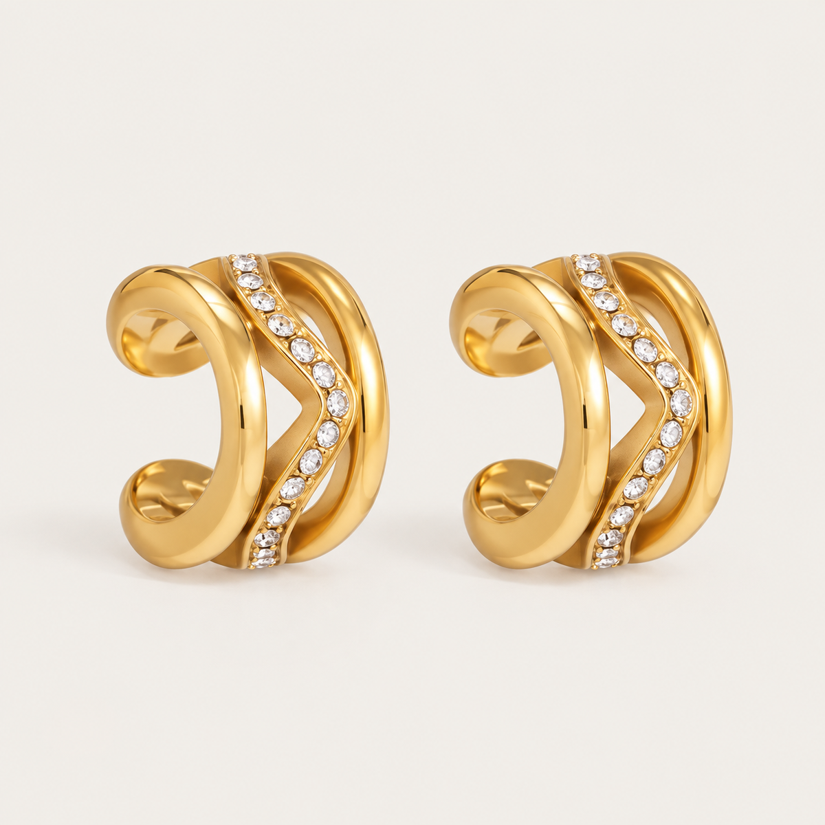 Pair of gold ear cuffs with layered wave bands and a diagonal row of pavé crystals, product shot for the Folie à Trois Wavelet EAR CUFF.