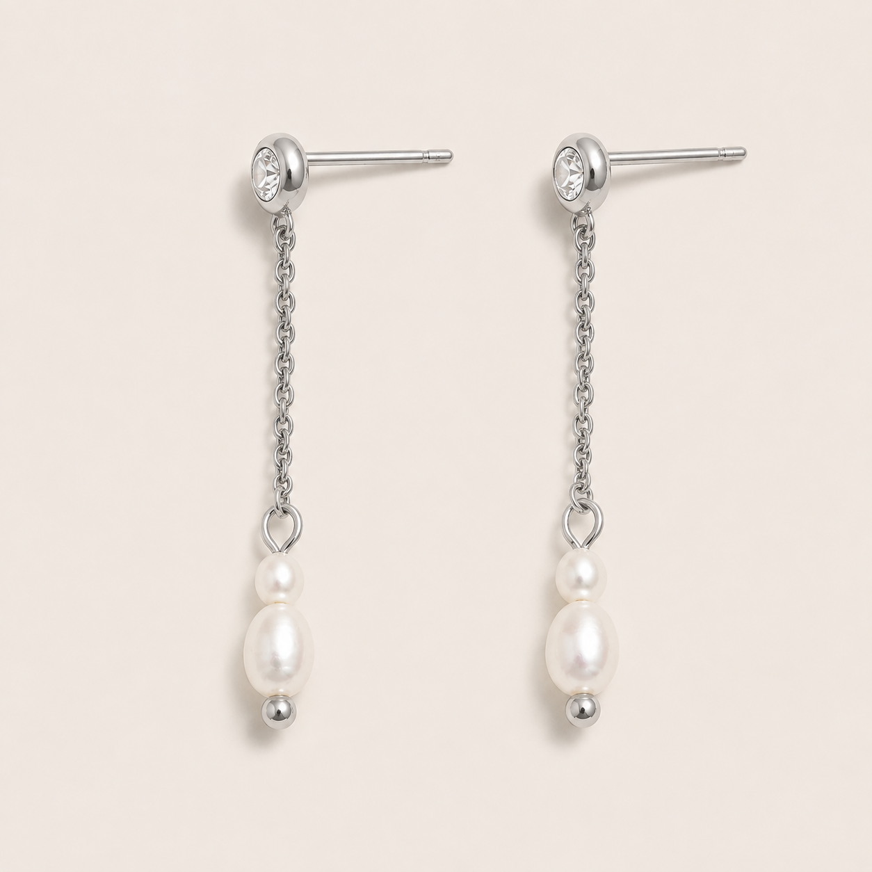 Silver drop earrings with a zirconia stud, fine chain and two freshwater pearls on a cream backdrop — Folie à Trois Whisper EARRINGS
