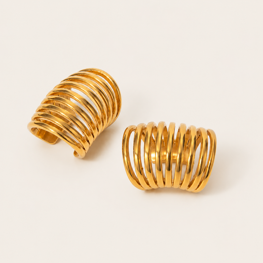 The Whitney EAR CUFF in a pair, a gold multi-band cuff made of several thin stacked rings, shown on a cream background.