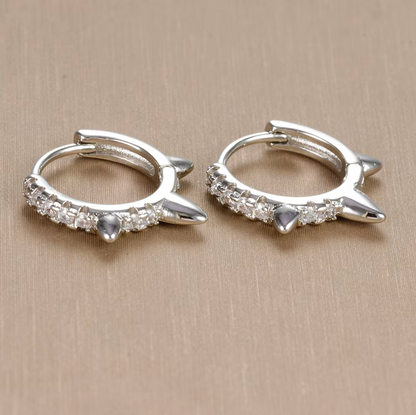 Close-up of Wild Earrings in silver tone on beige fabric, showing the pave spike detail on the hoop.