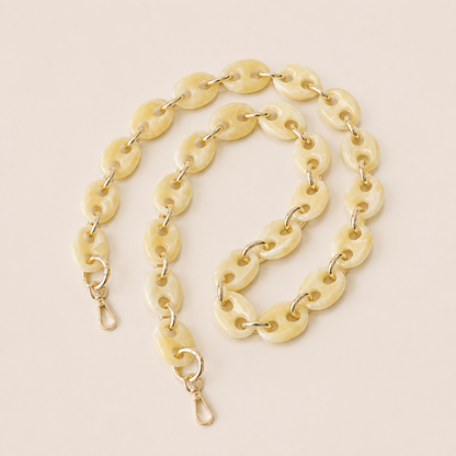 Folie à Trois Wilder long wholesale phone chain in ivory marbled puffed acetate links with gold connectors, coiled on a cream background.