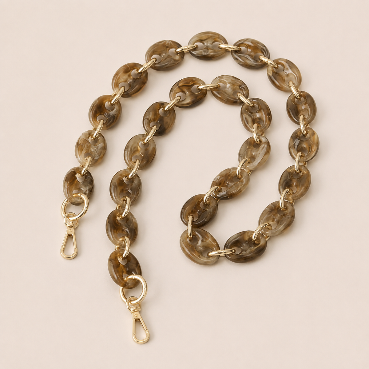 Folie à Trois Wilder long wholesale phone chain in coffee brown marbled puffed acetate links with gold connectors, coiled on a cream background.