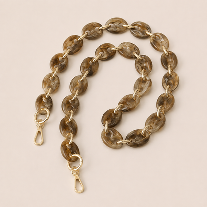 Folie à Trois Wilder long wholesale phone chain in coffee brown marbled puffed acetate links with gold connectors, coiled on a cream background.