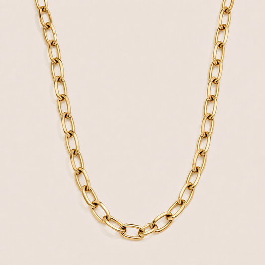 Gold oval-link cable chain necklace, the Wren NECKLACE, shown in a close-up studio shot on a soft beige background.