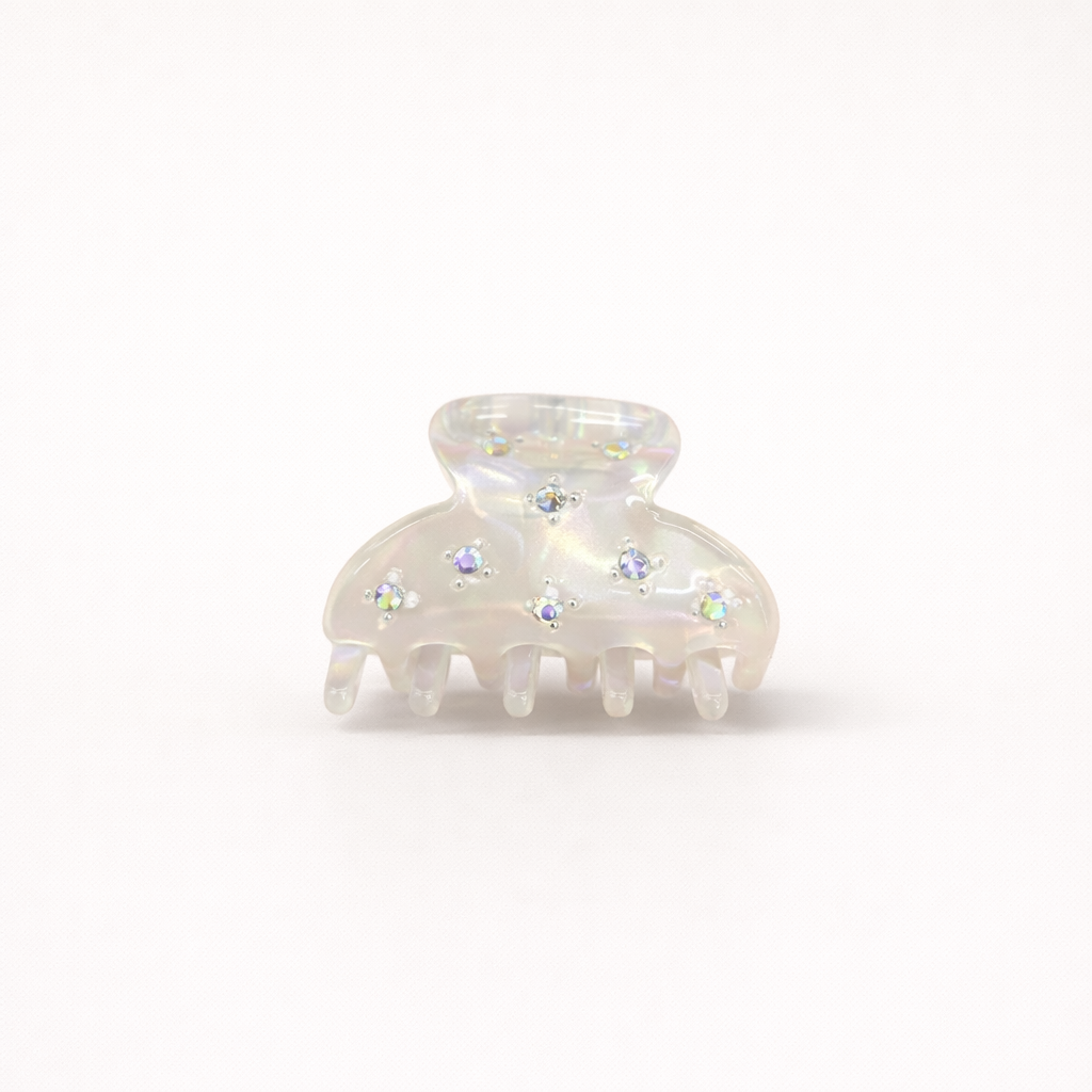 Yumi HAIR CLIP small acetate claw clip in iridescent white with crystal star accents, studio shot.
