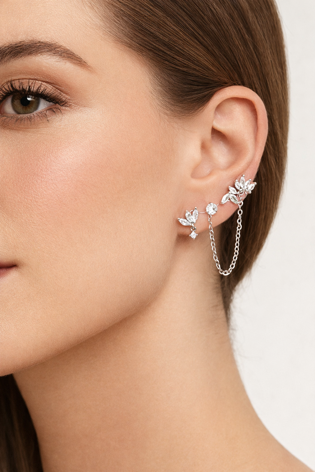 Worn along the ear, the silver Yvette SET layers leaf-cluster studs connected by a delicate draped chain.